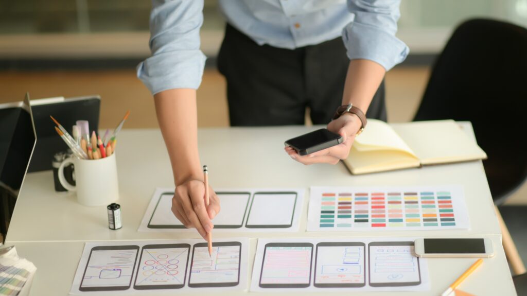 Young ux designer working on new application project while using smartphone in modern office room.